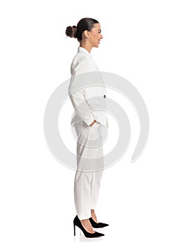elegant young woman with bun hair in white suit holding hands in pockets