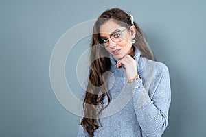 Elegant young woman in glasses and gray sweater isolated on a gray background with copy space