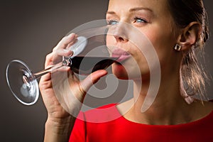 Elegant young woman having a glass of red wine