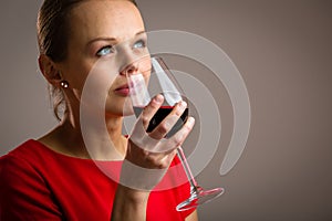 Elegant young woman having a glass of red wine