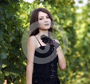 elegant young woman outdoor portrait lean on wall covered in vines