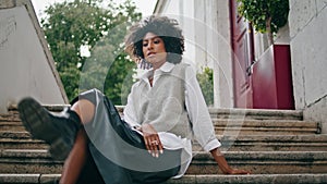 Elegant woman posing staircase looking camera close up. Girl sitting on stairs.