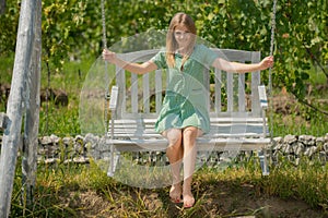 Elegant young woman swinging by vineyard. Outdoors lifestyle fashion portrait young girl enjoying on swing. Outdoor