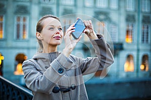 Elegant, young woman taking a photo with her cell phone camera