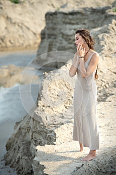 Elegant young woman in a trendy summer linen dress posing on the beach by the sea