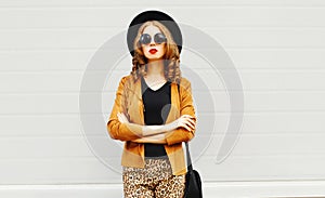 Elegant young woman wearing a retro elegant hat, sunglasses, brown jacket