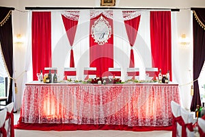 Elegantly catered wedding reception hall with red ribbons on lux