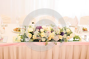 Elegantly decorated with white flowers, glasses and candles restaurant for celebrating wedding