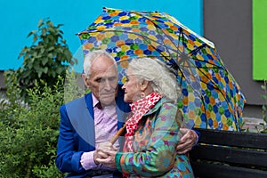 Elegantly dressed elderly couple sitting on a bench.