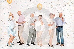 Elegantly dressed elderly people standing in a white room