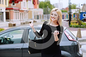 Elegantly dressed lady standing near car and holding car keys