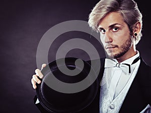 Elegantly dressed man holding black fedora hat