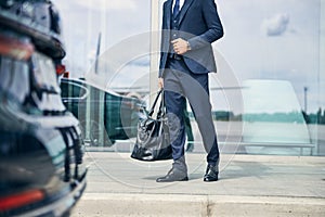 Elegantly dressed man walking towards an automobile