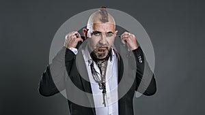 elegantly dressed punk man lifts lapels of his jacket looking defiantly at camera in studio shot