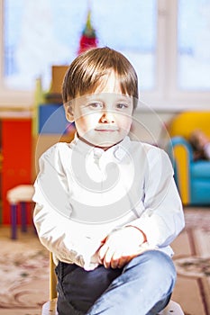 Elegantly dressed in a white shirt, a little boy is sitting in the classroom for lessons. portrait of a boy