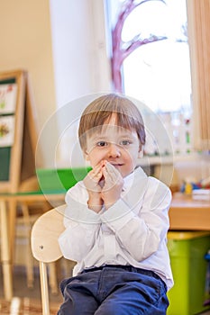 Elegantly dressed in a white shirt, a little boy is sitting in the classroom for lessons. portrait of a boy