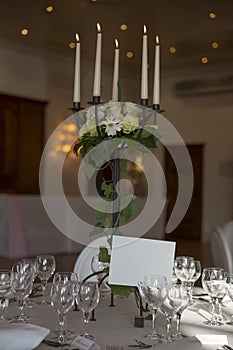 Elegantly served with wedding glasses, cutlery and decorated with flowers tables with white tablecloths and burning candles