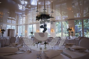 Elegantly served with wedding glasses, cutlery and decorated with flowers tables with white tablecloths and burning candles