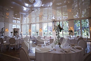 Elegantly served with wedding glasses, cutlery and decorated with flowers tables with white tablecloths and burning candles