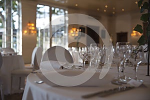 Elegantly served with wedding glasses, cutlery and decorated with flowers tables with white tablecloths and burning candles