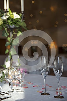Elegantly served with wedding glasses, cutlery and decorated with flowers tables with white tablecloths and burning candles