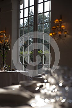 Elegantly served with wedding glasses, cutlery and decorated with flowers tables with white tablecloths and burning candles