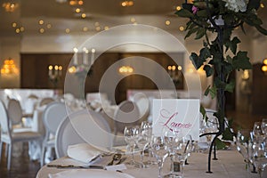 Elegantly served with wedding glasses, cutlery and decorated with flowers tables with white tablecloths and burning candles