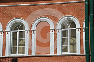 Element of the facade of a red brick building with white arched windows