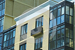 Multi-apartment urban residential building. Element of the facade of a brick building with glass windows and loggias photo