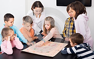 Elementary age calm children at table with board game and dice