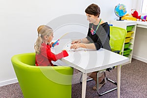 Elementary Age Girl in Child Occupational Therapy Session Doing Playful Exercises With Her Therapist. photo
