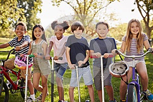 Elementary age school kids on bikes and scooters in a park