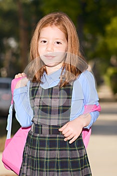 Elementary age schoolgirl in uniform with backpack