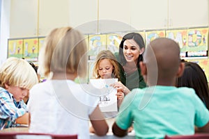 Elementary Pupil Showing Drawing To Classmates In Classroom