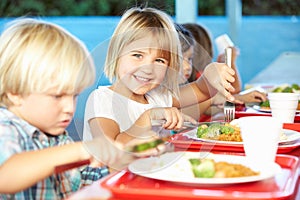 Elementary Pupils Enjoying Healthy Lunch In Cafeteria