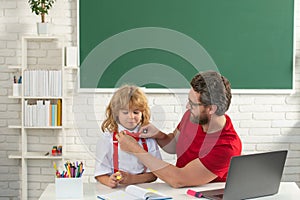 Elementary school boy in classroom on lesson. Teacher explaining to pupil. Teacher and child learning at school