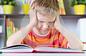 Elementary school boy at desk reading boock