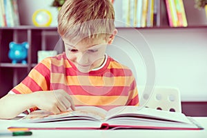 Elementary school boy at desk reading boock