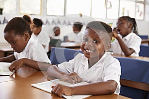 Elementary school boy smiling at camera at his desk in class