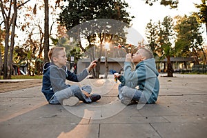 The elementary school boys are playing in the city. Blowing soap bubbles.