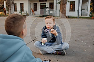 The elementary school boys are playing in the city. Blowing soap bubbles.