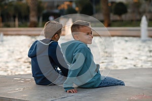 The elementary school boys are playing at the city fountain.