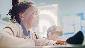 In Elementary School Classroom Black Girl Writes in Exercise Notebook, Taking Test. Junior Classro