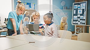 Elementary School Computer Science Class: Two Girls and Boy Use Digital Tablet Computer with