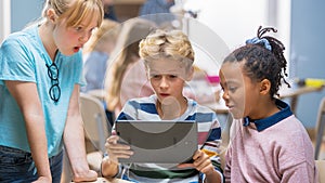 Elementary School Computer Science Class: Two Girls and Boy Use Digital Tablet Computer with