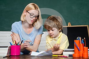 Elementary school - education and learning child concept. Teacher helping young boy with lesson. Great study achievement