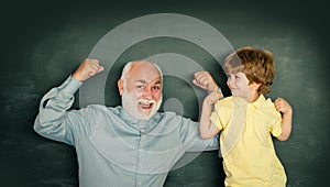 Elementary school kid and teacher with laptop in classroom at school. Grandfather with grandson learning lesson together