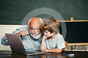 Elementary school, kid and teacher with laptop in classroom at school. Teacher and schoolboy using computer in class