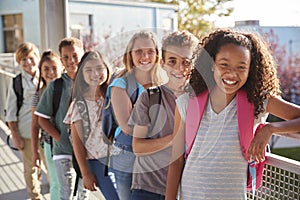 Elementary school kids with backpacks smiling at the camera