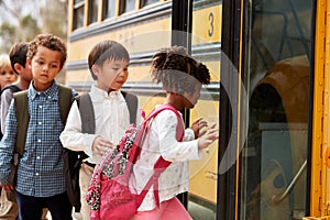 Elementary school kids climbing on to a school bus